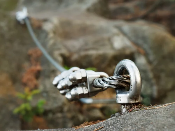 Iron twisted rope streched between rocks in climbers patch.  Rope fixed in block by screws snap hooks. Detail of rope . — Stock Photo, Image