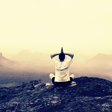 Adam kayalar tepe üzerinde Yoga poz puslu sabah içinde yapıyor