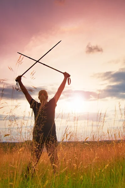 Happy girl  hiker with crossed poles in evening golden meadow — Stock Photo, Image