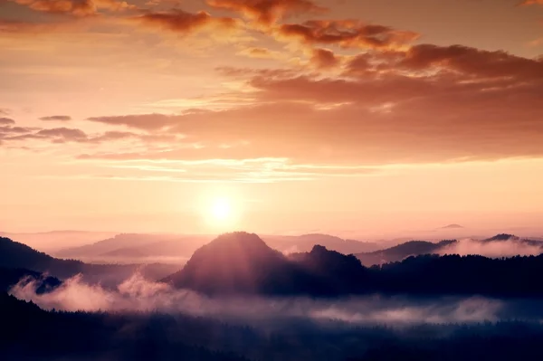 Neblig-verträumte Landschaft mit Herbstnebel zwischen Hügeln und orangefarbenem Himmel bei frühem Sonnenaufgang — Stockfoto