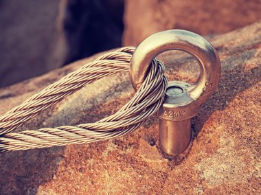 Çelik cıvata çapa göz kaya ayrıntı. Çelik halat bitiş düğüm. Via ferrata kaya dağcılar yolunda. Demir blok içinde sabit ip bükülmüş.