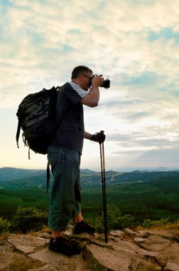 Fotoğrafçı büyük ayna kamera boyun ve sırt çantası ile kaya tepe üzerinde kal. Dağlık manzara, taze yeşil renk Vadisi.