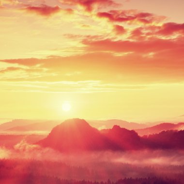 Kırmızı puslu daybreak. Sisli sonbahar sabahı güzel Hills. Hills doruklarına zengin renkli bulutlar yapışkanlık dışarı.