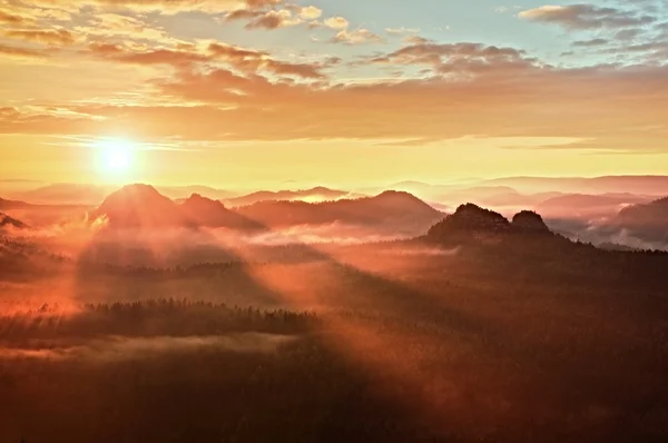 赤霧の夜明け。美しい丘の秋霧の朝。丘のピークは豊かなカラフルな雲から出ています。. — ストック写真