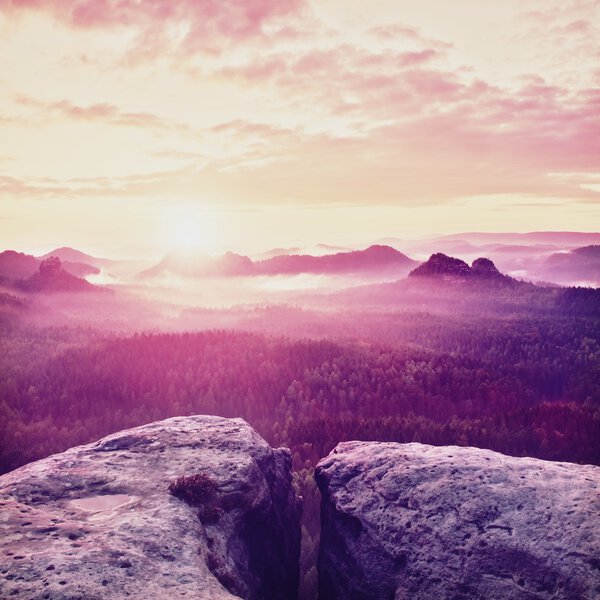 misty  landscape panorama in mountains. Fantastic dreamy sunrise on rocky mountains with view down to foggy misty valley below