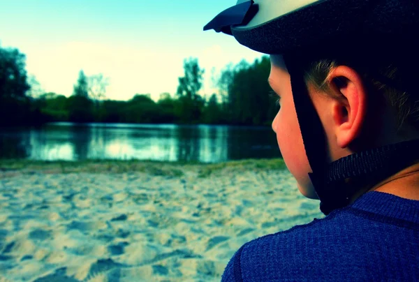 Ragazzino con casco da bicicletta testa, vestito in abbigliamento sportivo sulla spiaggia — Foto Stock