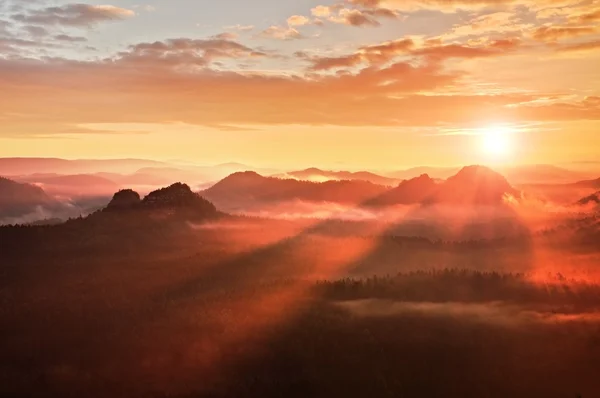 Amanhecer enevoado vermelho. Foggy manhã de outono em umas belas colinas. Picos de colinas estão saindo de nuvens coloridas ricas . — Fotografia de Stock