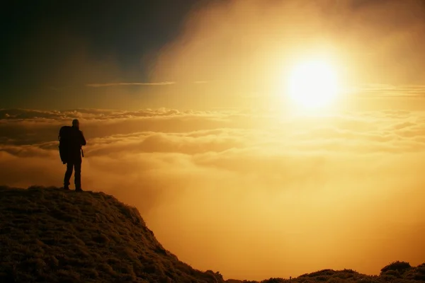 Alto excursionista adulto en negro en la cima del mundo. Niebla naranja pesada bramido en el valle. Maravilloso amanecer en las montañas . — Foto de Stock
