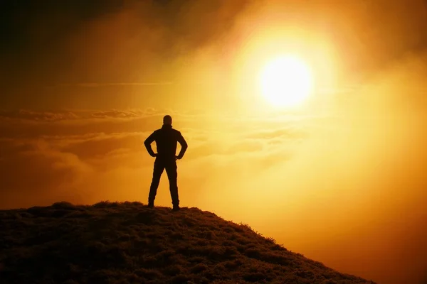 Alto excursionista adulto en negro en la cima del mundo. Niebla naranja pesada bramido en el valle. Maravilloso amanecer en las montañas . — Foto de Stock