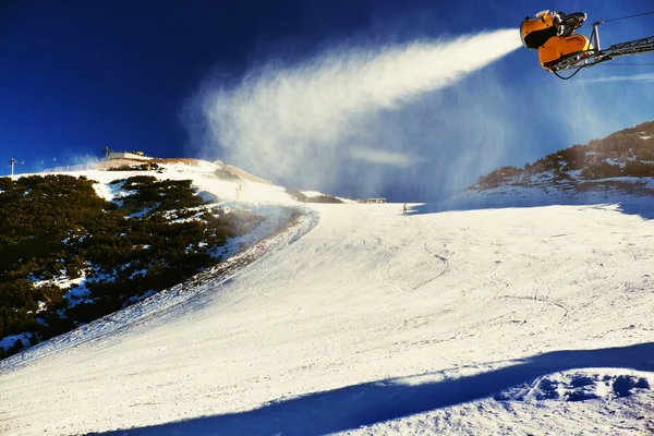 Skier near a snow cannon making powder snow. Alps ski resort. — Stock Photo, Image