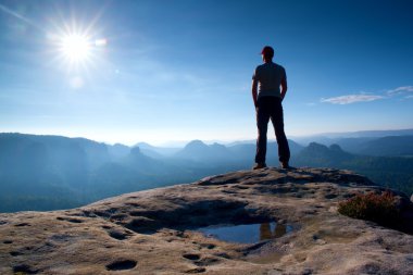 Yalnız adam rock empires park ve güneş güzel an puslu ve sisli sabah Vadisi'ne üzerinden izlerken keskin tepe tepe üzerinde kırmızı şapkalı