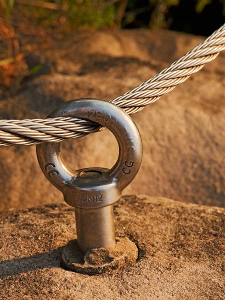 Detalle de ojo de anclaje de perno de acero en roca arenisca. El nudo final de la cuerda de acero. Escaladores camino a través de ferrata. Cuerda retorcida de hierro fijada en bloque . — Foto de Stock