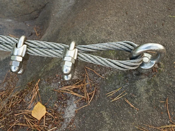 Detail of steel bolt anchor eye in rock. The end knot  of steel rope. Climbers path in rocks via ferrata. Iron twisted rope fixed in block. — Stock Photo, Image