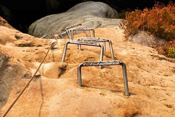 登山者は金属ヴィア フェラータはしごです。鉄ネジ スナップ フックでブロックの固定ロープのツイスト。砂岩の岩にアンカー ロープの端. — ストック写真