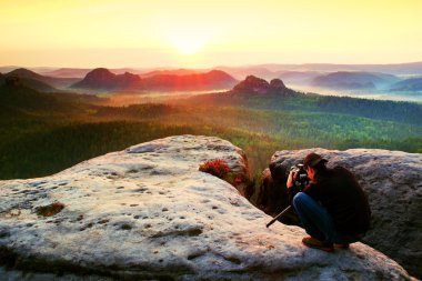 Tripod üzerinde cliff ve düşünme ile profesyonel fotoğrafçı. Rüya gibi adamlara manzara, bir güzel sisli vadide puslu sunrise