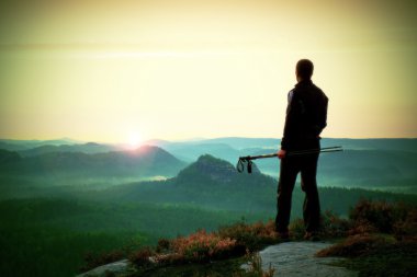 Turist silüeti Polonyalılar ile el kılavuzu. Uzun yürüyüşe çıkan kimse sportif spor giyim ile keskin görüş noktası puslu Vadisi üzerinde durmak. Rocky Dağları'nda güneşli gün doğumuna.