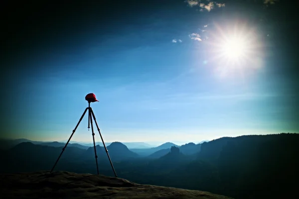 写真の準備ができてのピークに赤い野球帽と三脚。濃霧から増加したシャープの秋岩の峰 々. — ストック写真
