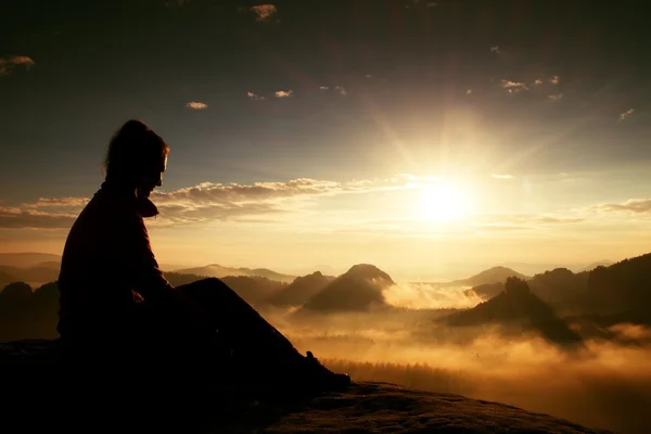 Beautiful  young long hair girl tourist enjoy daybreak on the sharp corner of sandstone rock and watch over valley to Sun. — Stock Photo, Image