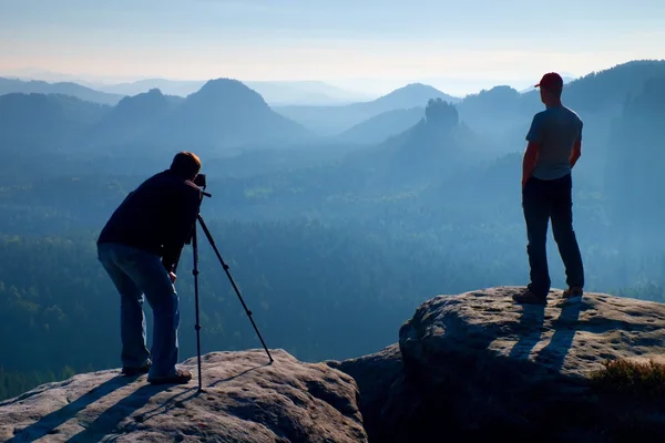 Tripod cliff ve düşünme üzerinde Turist Rehberi ve fotoğraf tutkunu kal. Rüya gibi adamlara manzara, mavi puslu gündoğumu bir güzel vadi