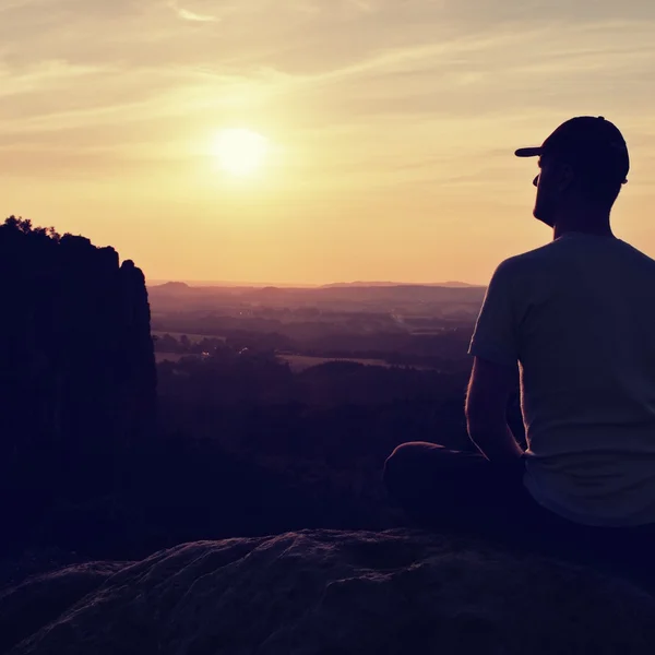 Man met Baseballpet bovenop de berg. Silhouet van rotsen. — Stockfoto