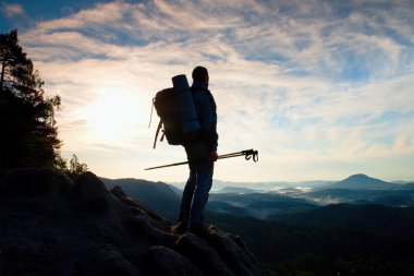Turist kılavuz milyon verseler elinde. Uzun yürüyüşe çıkan kimse sportif sırt çantası ile kayalık Görünüm noktası puslu Vadisi üzerinde durmak. Güneşli Bahar şafak
