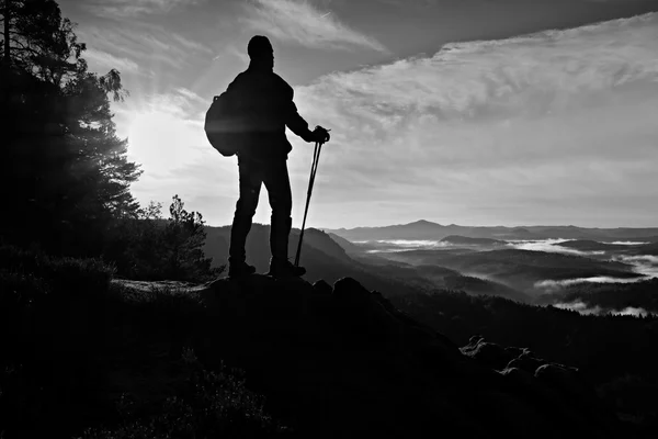 Turistický průvodce s batohem na rock a sledování do hlubokých mlhavé údolí vlnovec. — Stock fotografie