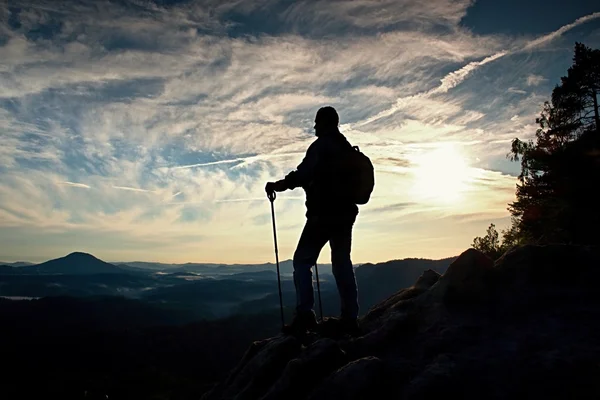 Туристический гид с рюкзаком на скале и глядя в глубокую туманную долину ниже . — стоковое фото