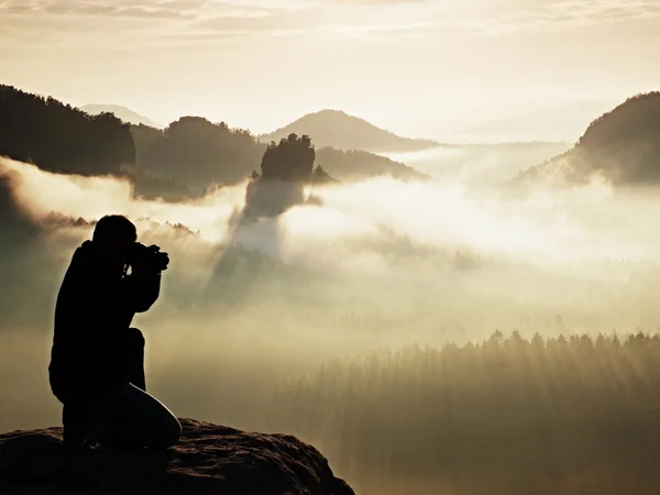 Sílhueta de fotógrafo profissional acima de um mar de nuvens, montanhas nebulosas — Fotografia de Stock