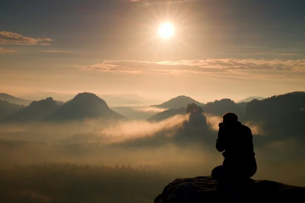 Fotografia tira fotos de amanhecer acima pesado vale nebuloso. Vista paisagem de nebulosas colinas de outono e silhueta de homem feliz — Fotografia de Stock