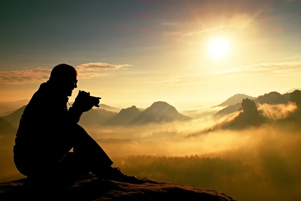 La photographie prend des photos du lever du jour au-dessus d'une vallée brumeuse. Vue paysage de collines de montagne d'automne brumeux et silhouette homme heureux — Photo