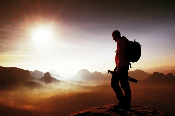 Silhouette of photographer overlooking a blanket of fog over valley to sun — Stock Photo, Image