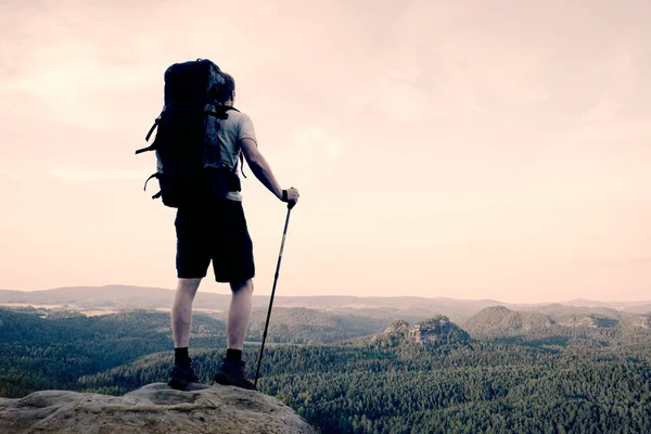 Ψηλό backpacker με πόλους στο χέρι. Ηλιόλουστο καλοκαίρι evenng στην Βραχώδη Όρη. Πεζοπόρος με μεγάλο σακίδιο σταθεί στα βραχώδη οπτική γωνία πάνω από το κοιλάδα. — Φωτογραφία Αρχείου