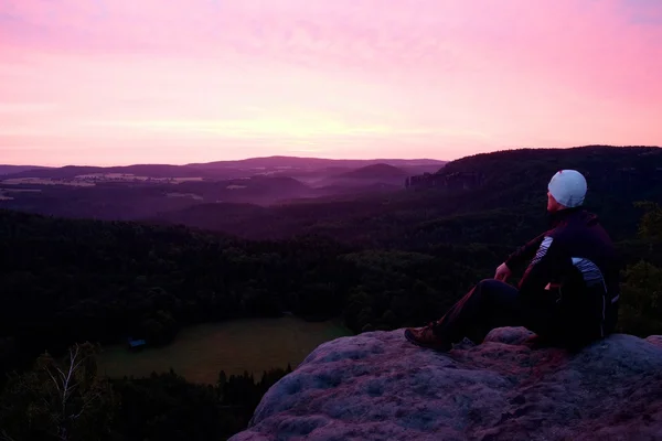 Um desportista se senta em uma rocha e assiste à paisagem da manhã abaixo — Fotografia de Stock