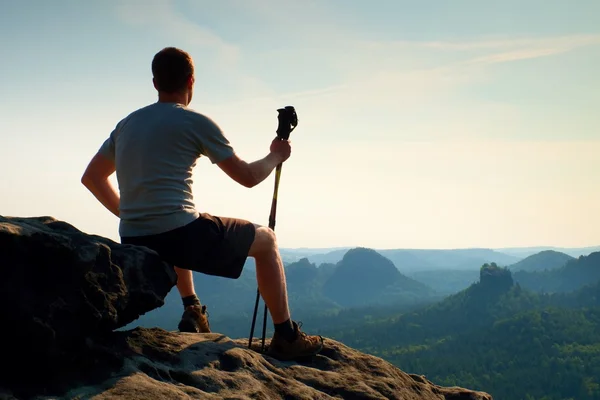 Moe vergadering toeristische met stokken in de hand. Zonnige voorjaar daybreak in rocky mountains. Wandelaar met het volgen van Polen zitten op rotsachtige oogpunt — Stockfoto