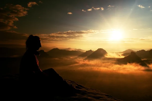 Beautiful  young long hair girl tourist enjoy daybreak on the sharp corner of sandstone rock and watch over valley to Sun. — Stock Photo, Image