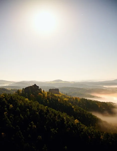 Cold misty daybreak in a fall valley of Bohemian Switzerland park. Hill with hut on the peak increased from magical darkness. — Stock Photo, Image