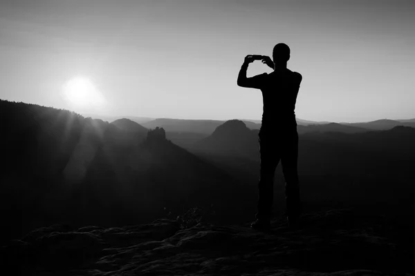 Vandrare tar foto på toppen av berget smart telefon på sunrise. — Stockfoto