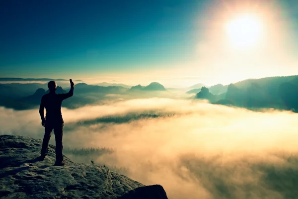 Caminhante está tirando foto por telefone inteligente no pico da montanha ao nascer do sol . — Fotografia de Stock