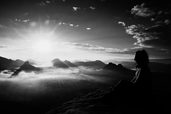 Beautiful  young long hair girl tourist enjoy daybreak on the sharp corner of sandstone rock and watch over valley to Sun. — Stock Photo, Image