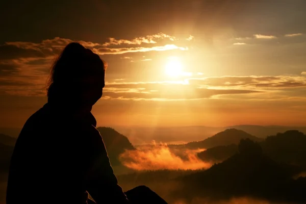 Beautiful  young long hair girl tourist enjoy daybreak on the sharp corner of sandstone rock and watch over valley to Sun. — Stock Photo, Image