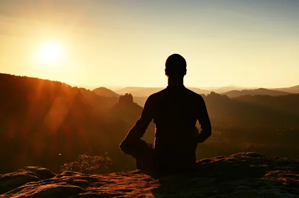 Hiker in squatting position on a rock, enjoy dybreak  scenery — Stock Photo, Image