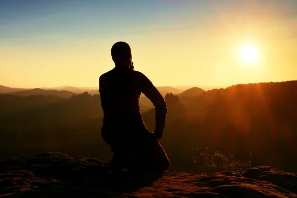 Sportsmann vandrer i sort sportstøj sidde på bjergtoppen og tage en pause. Turist se ned til morgen diset dal . - Stock-foto