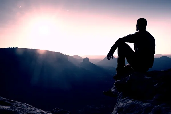 Senderista tomar relajarse en una roca y disfrutar de la puesta de sol en el horizonte. Efecto vívido . — Foto de Stock