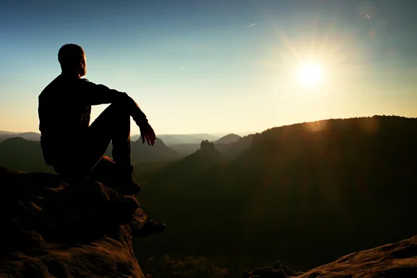 Caminhante relaxar em uma rocha e desfrutar do pôr do sol no horizonte. Efeito vívido . — Fotografia de Stock