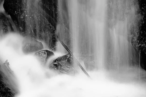 Spray d'acqua sotto la piccola cascata sul torrente di montagna, l'acqua sta cadendo sul masso muscoloso. Lo spray crea a livello e ghiaia acqua lattiginosa. Rami rotti in acqua — Foto Stock