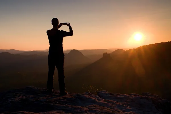 Turysta bierze Zdjęcie przez inteligentny telefon na szczyt góry na wschód. — Zdjęcie stockowe