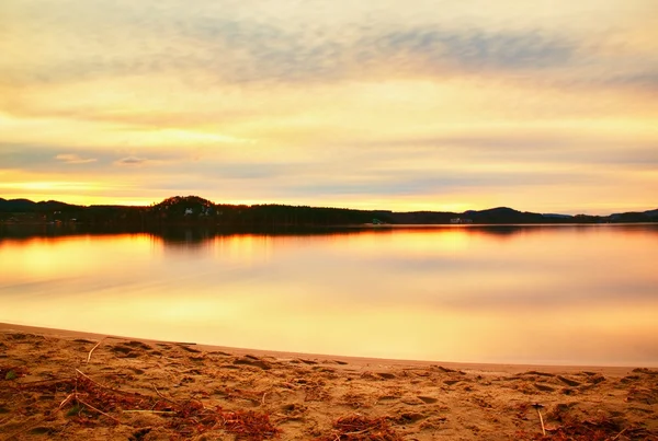 Playa de arena abandonada en el lago antes del atardecer de otoño, rayos de sol entre nubes y reflejos en el nivel del agua —  Fotos de Stock