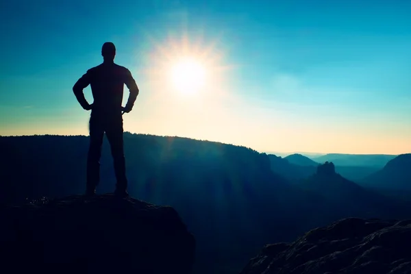 Een man heeft zijn handen op de heupen. Sportman silhouet in de natuur bij het aanbreken van de dag. — Stockfoto