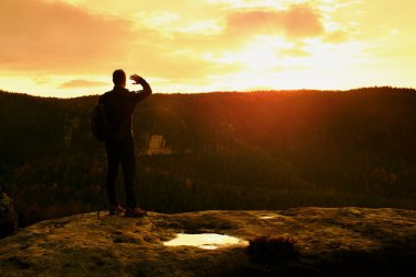 Turist kılavuz kutup ile yolda elinde. Uzun yürüyüşe çıkan kimse sportif sırt çantası ile kayalık Görünüm noktası puslu Vadisi üzerinde durmak. Güneşli bahar daybreak kayalarda