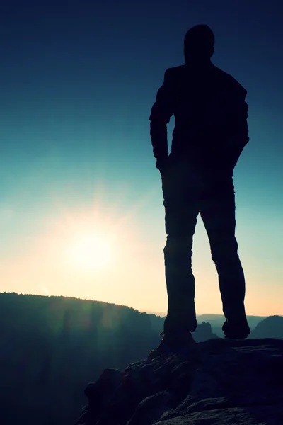 Silueta de hombre joven confiado y poderoso de pie con las manos en las caderas, el sol de la mañana o del último día con espacio de copia — Foto de Stock